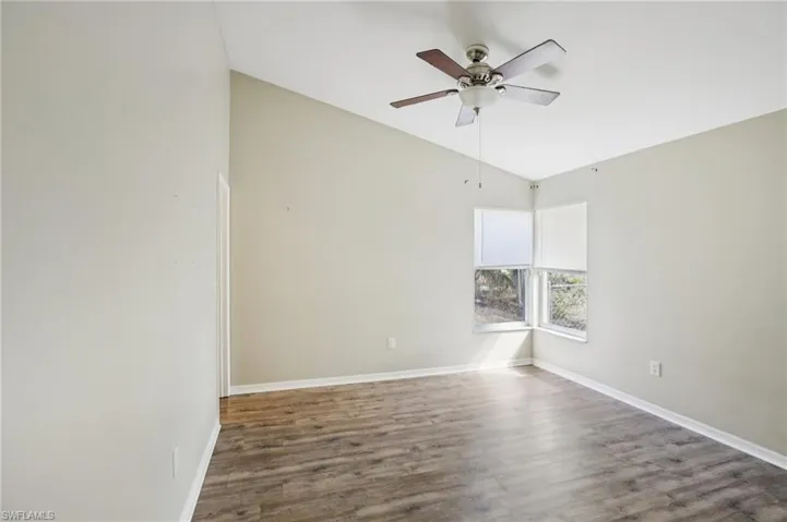 Empty room with wood finished floors, ceiling fan, and lofted ceiling