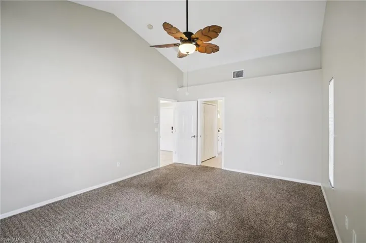 Unfurnished bedroom with lofted ceiling, carpet floors, and a ceiling fan