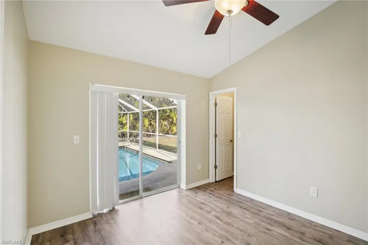 Empty room featuring a sunroom, ceiling fan, wood finished floors, and vaulted ceiling