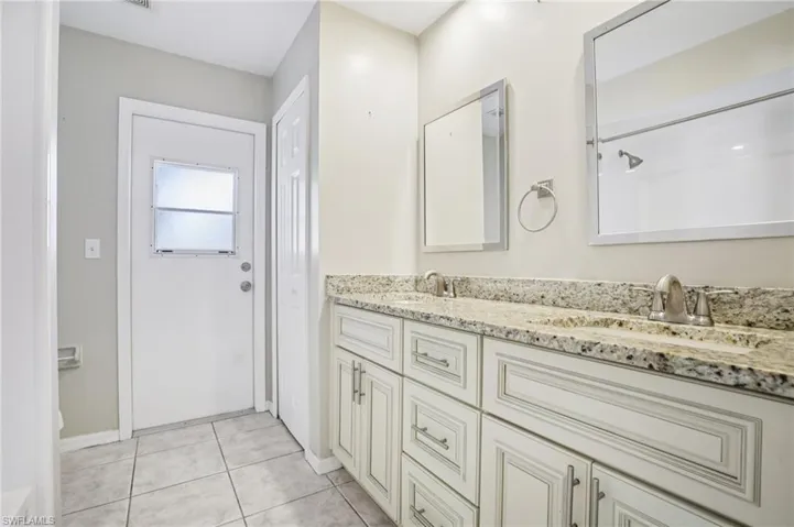 Full bath featuring double vanity and light tile patterned floors