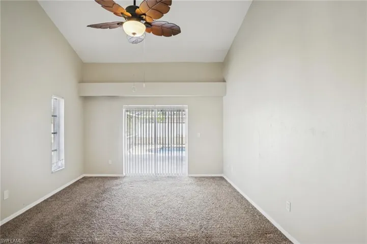 Spare room featuring a ceiling fan, carpet flooring, and lofted ceiling
