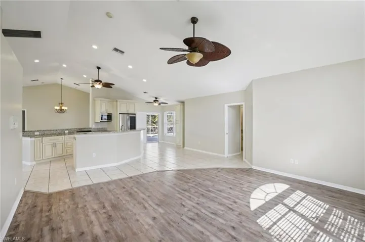 Unfurnished living room featuring light wood finished floors, lofted ceiling, and hanging lights
