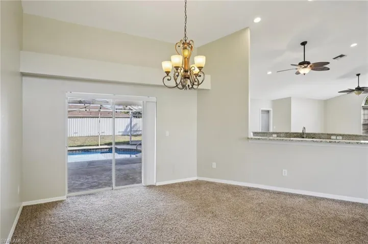 Unfurnished dining area featuring ceiling fan, light carpet, lofted ceiling, and suspended lighting