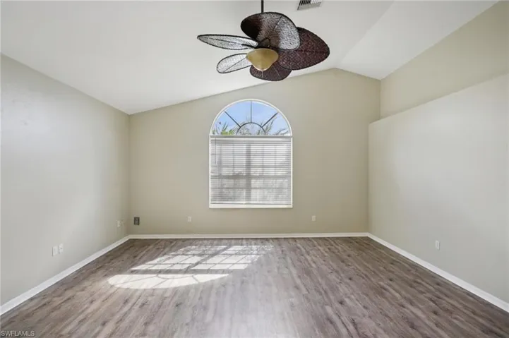 Empty room with vaulted ceiling, wood finished floors, and ceiling fan