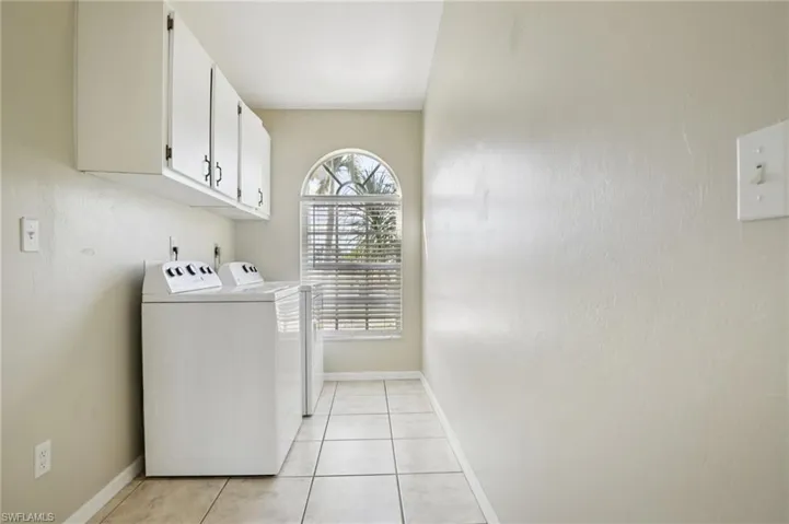 Laundry room with cabinet space, separate washer and dryer, and light tile patterned floors