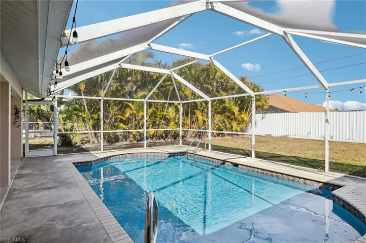 View of swimming pool with a sunroom, a fenced backyard, and patio surround