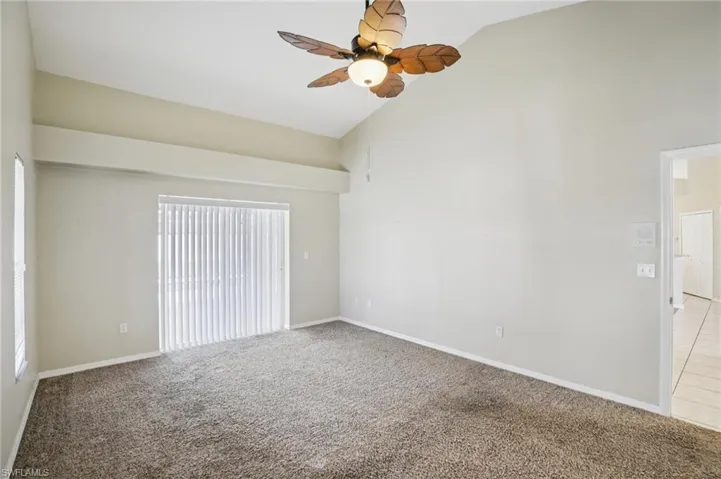 Empty room featuring carpet flooring, ceiling fan, and lofted ceiling