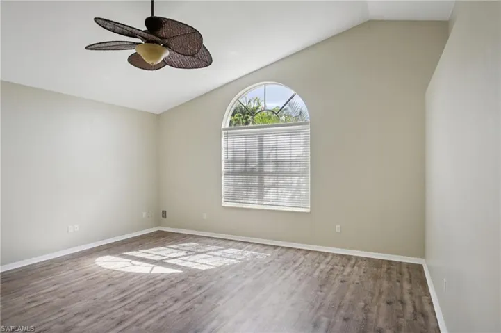Empty room with lofted ceiling, wood finished floors, and a ceiling fan