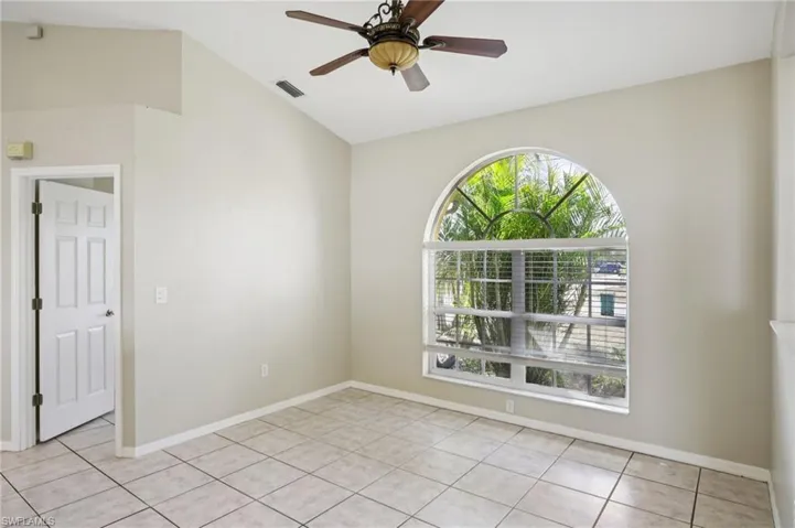 Empty room featuring a ceiling fan, vaulted ceiling, and light tile patterned flooring