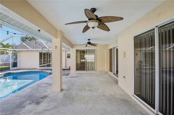 Outdoor pool featuring a sunroom, a patio area, and glass enclosure