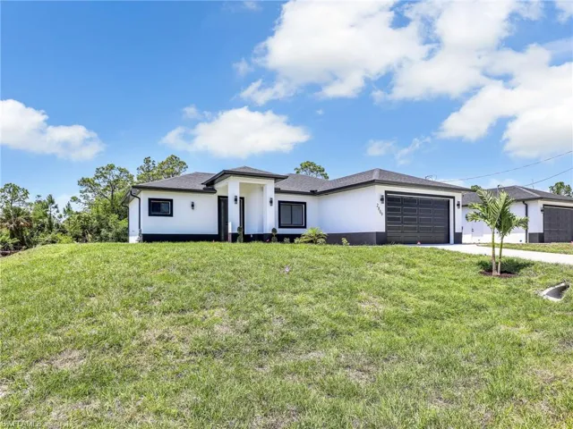 Prairie-style house with stucco siding, concrete driveway, a front lawn, and a garage
