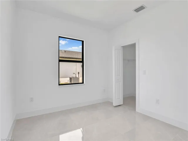 Unfurnished bedroom featuring a walk in closet, visible vents, and baseboards
