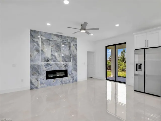 Unfurnished living room featuring light tile patterned floors, a high end fireplace, baseboards, recessed lighting, and a ceiling fan