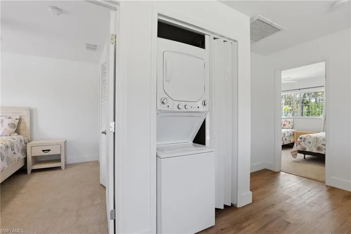 Laundry room featuring stacked washing machine and dryer and baseboards