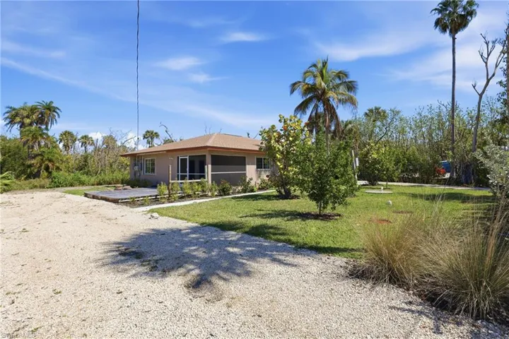View of front of house with a front lawn and gravel driveway