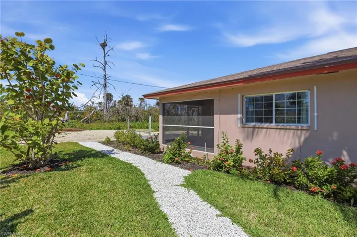 View of grassy yard featuring a sunroom