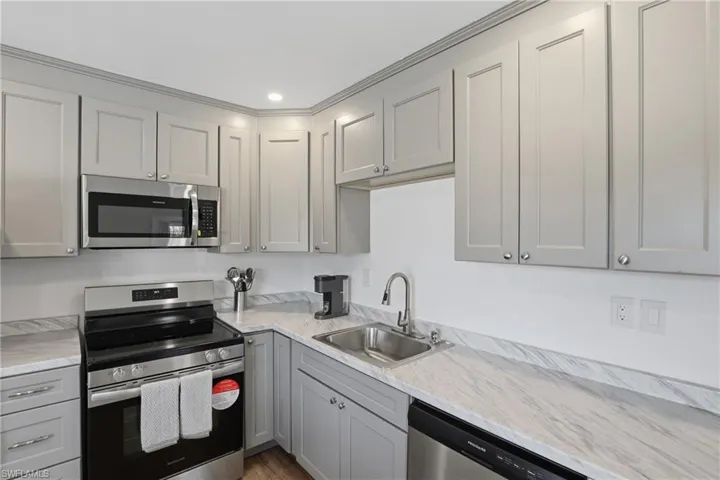 Kitchen with gray cabinetry, stainless steel appliances, recessed lighting, and light wood finished floors
