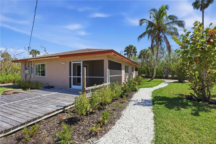 View of home's exterior featuring a lawn, a wooden deck, stucco siding, and a sunroom
