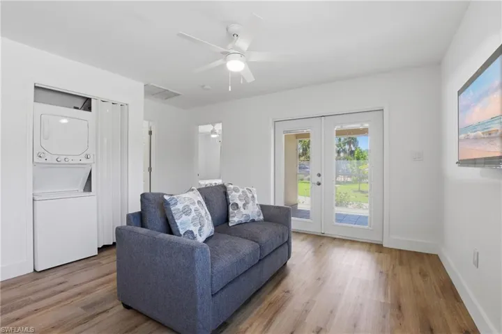 Living room featuring french doors, stacked washing machine and dryer, wood finished floors, and ceiling fan
