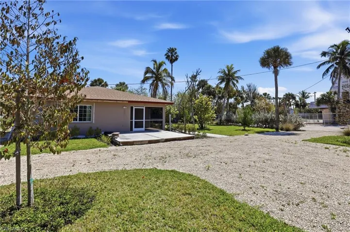 Back of property with a lawn, stucco siding, a sunroom, a patio area, and roof with shingles