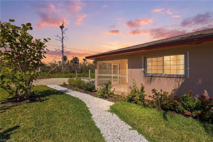 Property exterior at dusk with stucco siding, a yard, and a sunroom
