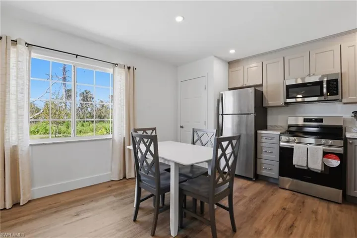 Kitchen with stainless steel appliances, gray cabinets, light wood-style floors, recessed lighting, and light stone counters