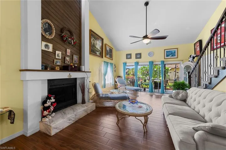 Living area with a ceiling fan, a premium fireplace, wood finished floors, high vaulted ceiling, and stairway