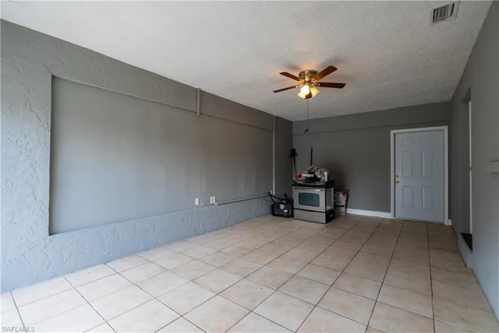 Unfurnished living room with a ceiling fan, a textured wall, and a textured ceiling