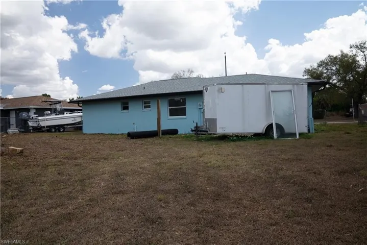 Back of house featuring roof with shingles and a yard