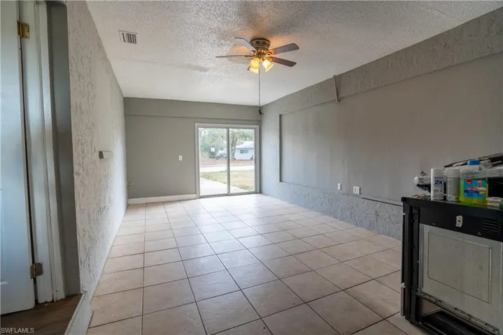 Unfurnished room with a textured wall, ceiling fan, a textured ceiling, and light tile patterned floors