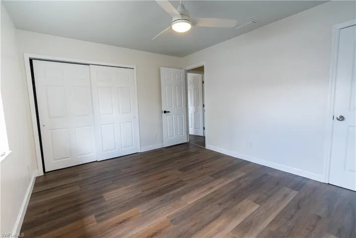 Unfurnished bedroom with a ceiling fan, dark wood finished floors, and a closet