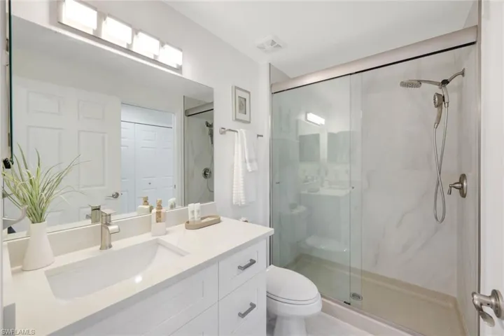 Bathroom featuring vanity, toilet, and a walk-in shower