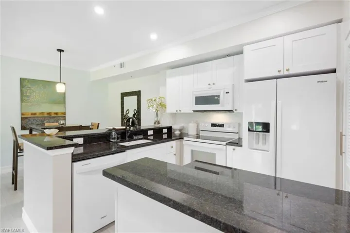 Kitchen featuring pendant lighting, granite counters, sink, white cabinetry, and white appliances
