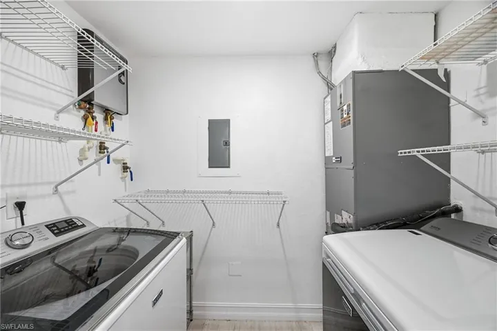 Laundry room featuring tankless water heater, washer and dryer