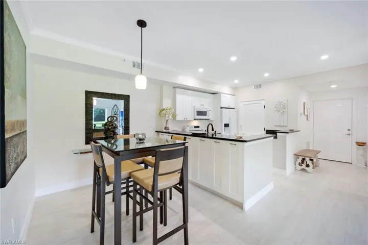 Kitchen with pendant lighting, sink, white cabinetry, white appliances, and crown molding