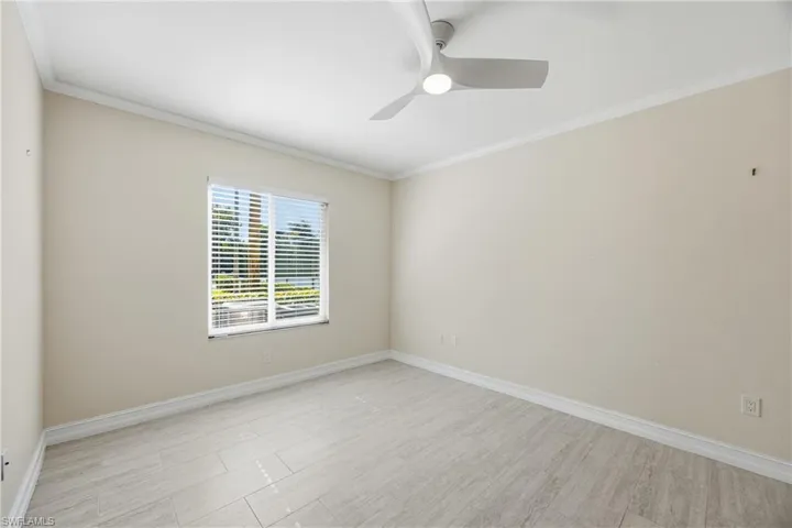 primary bedroom with crown molding, a ceiling fan, and light tile floors