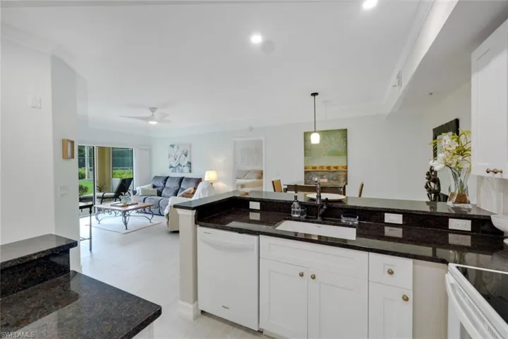 Kitchen featuring white cabinets, white appliances, granite countertops, and sink