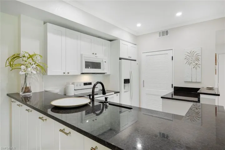 Kitchen featuring crown molding, granite countertops, white appliances, and white cabinets