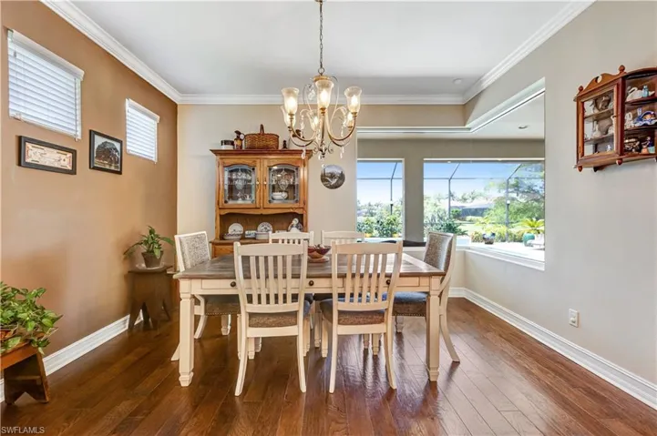 Dining room featuring a chandelier, dark wood-type flooring, ornamental molding, and baseboards