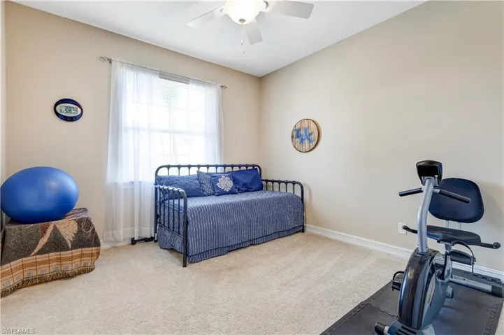 Exercise area featuring carpet flooring, a ceiling fan, and baseboards