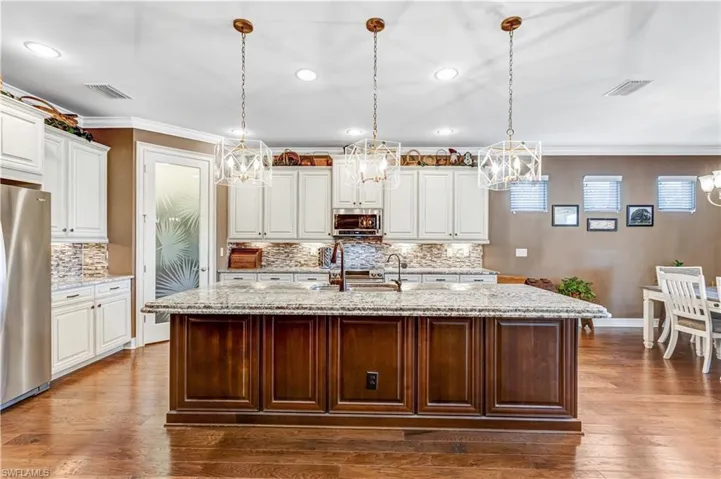 Kitchen featuring stainless steel appliances, a sink, a chandelier, baseboards, and ornamental molding