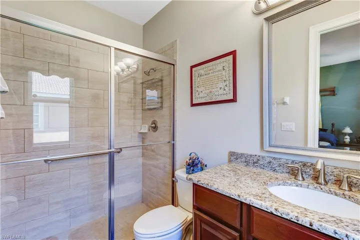 Ensuite bathroom featuring a stall shower, vanity, and toilet