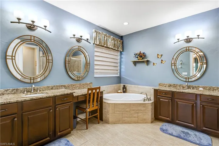Full bathroom featuring a bath, two vanities, and tile patterned floors