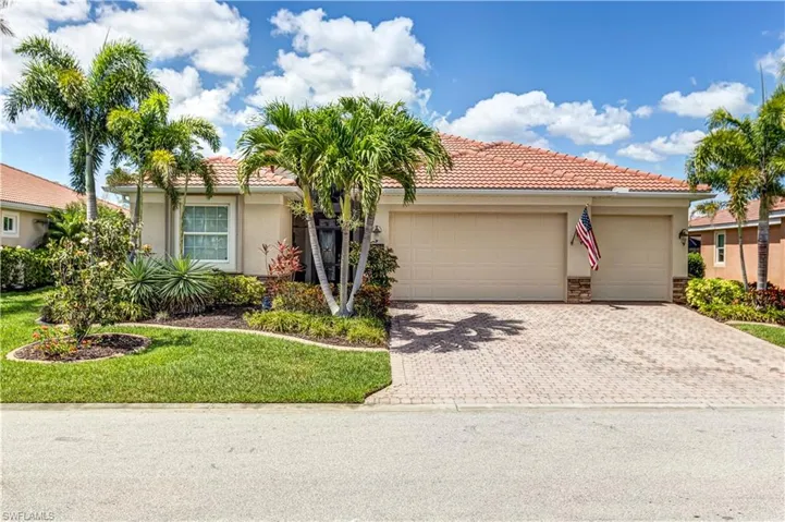 View of front facade featuring stucco siding, driveway, a tiled roof, and a garage