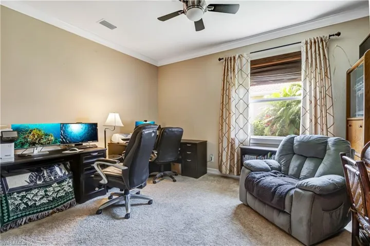 Carpeted office space featuring crown molding, a ceiling fan, and baseboards