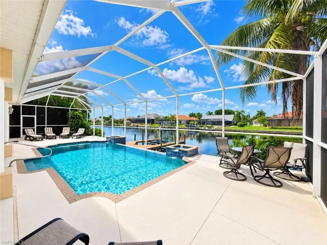 Screened lanai with a rectangular pool, integrated spa, and expansive pool deck