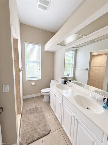 Dual vanity with white cabinetry, integrated sinks, and a large mirror
