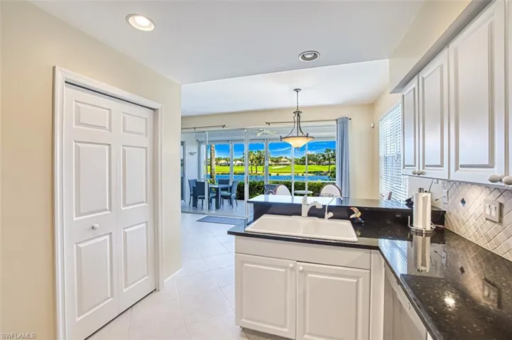 Kitchen with hanging light fixtures, a peninsula, a sink, and white cabinets