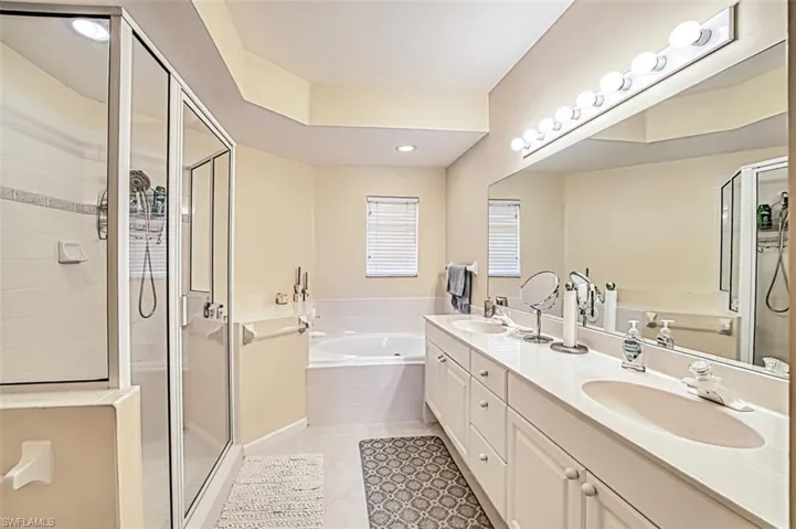 Bathroom featuring a garden tub, tile patterned flooring, a sink, a shower stall, and double vanity