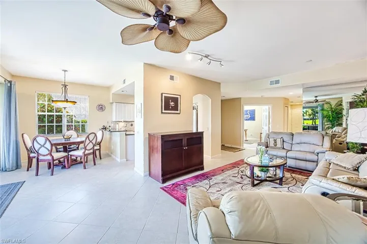 Living room featuring arched walkways, visible vents, ceiling fan, and light tile patterned flooring